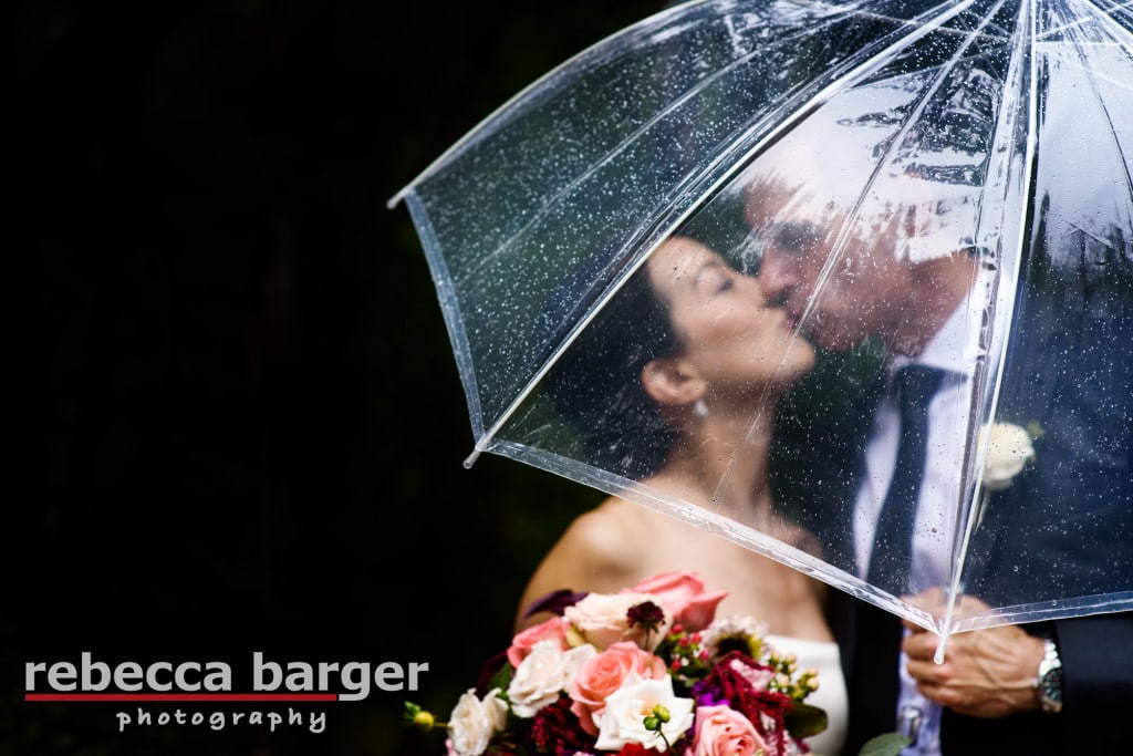 Karen + Jim have a romantic wedding day kiss under the umbrella at Pomme, a Peachtree and Ward venue.