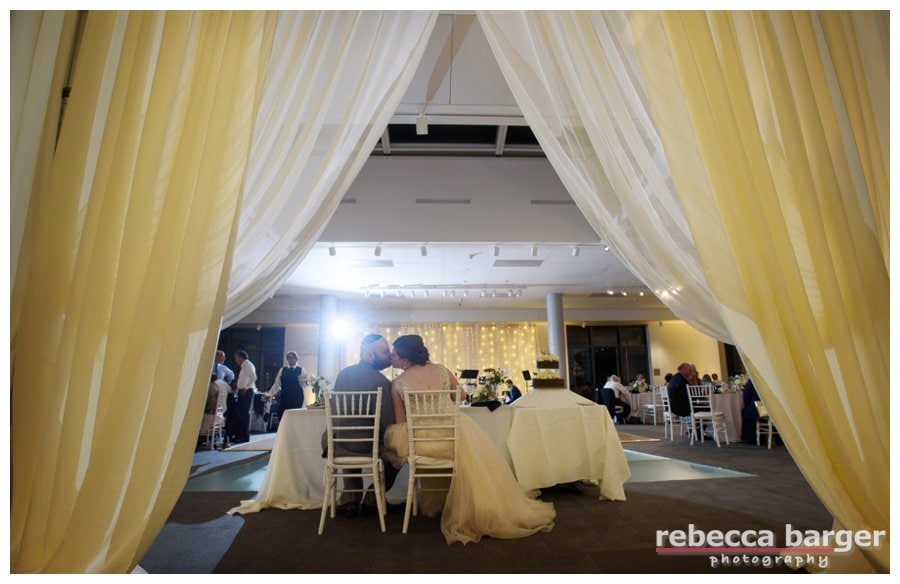 Peeking through the drapery at the newlyweds enjoying their meal at their NMAJH wedding reception. Lighting and drapery by Shipley Enterprises.