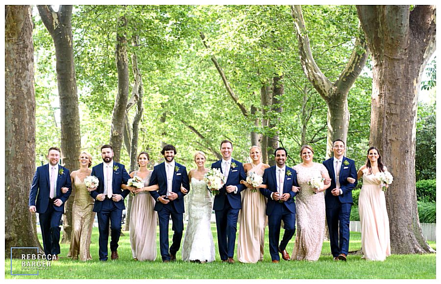 A gorgeous bridal party walking amongst the trees on the way to the wedding at The Free Library of Philadelphia, Brûlée Catering.